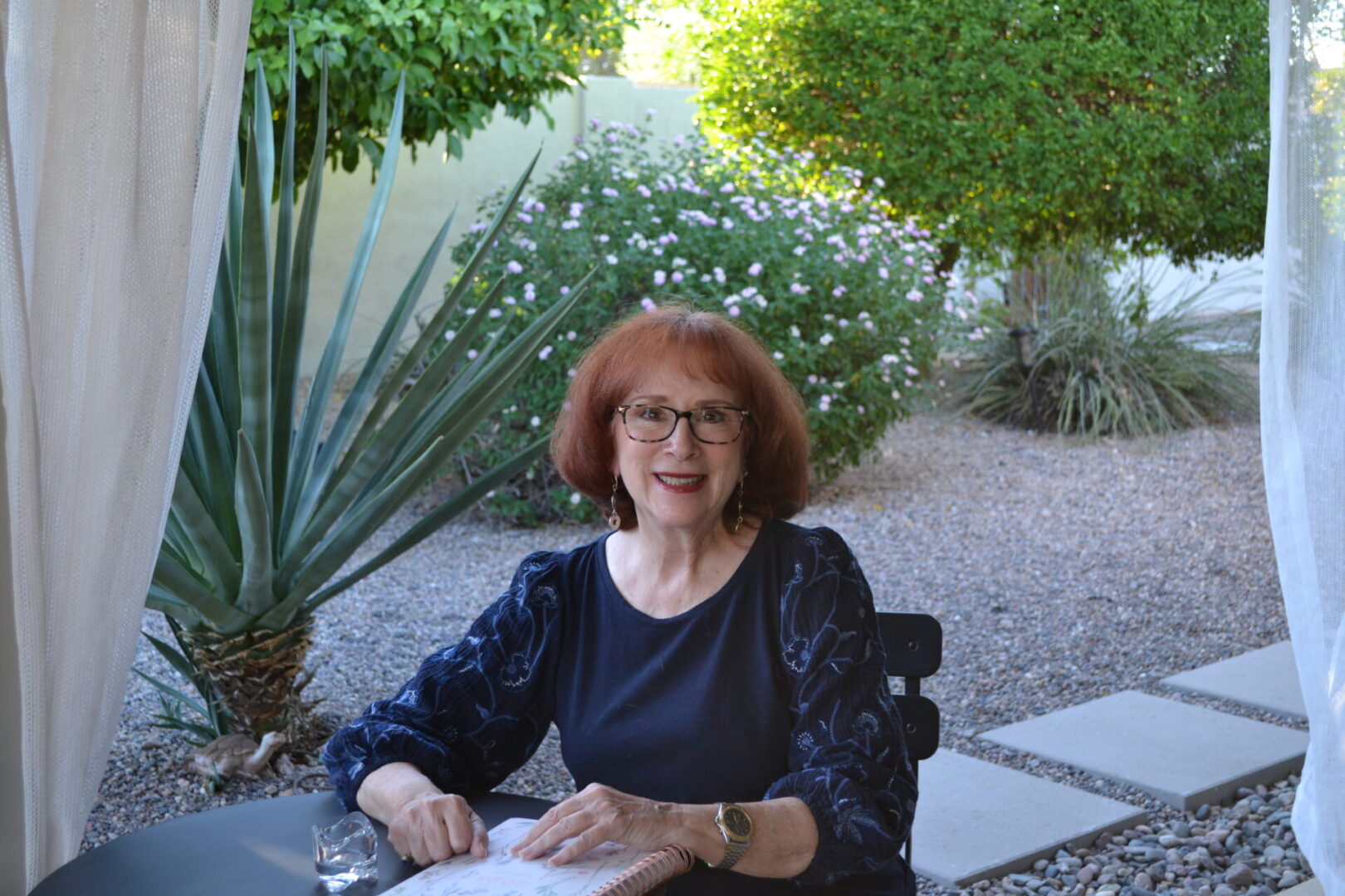 A woman sitting in front of some bushes